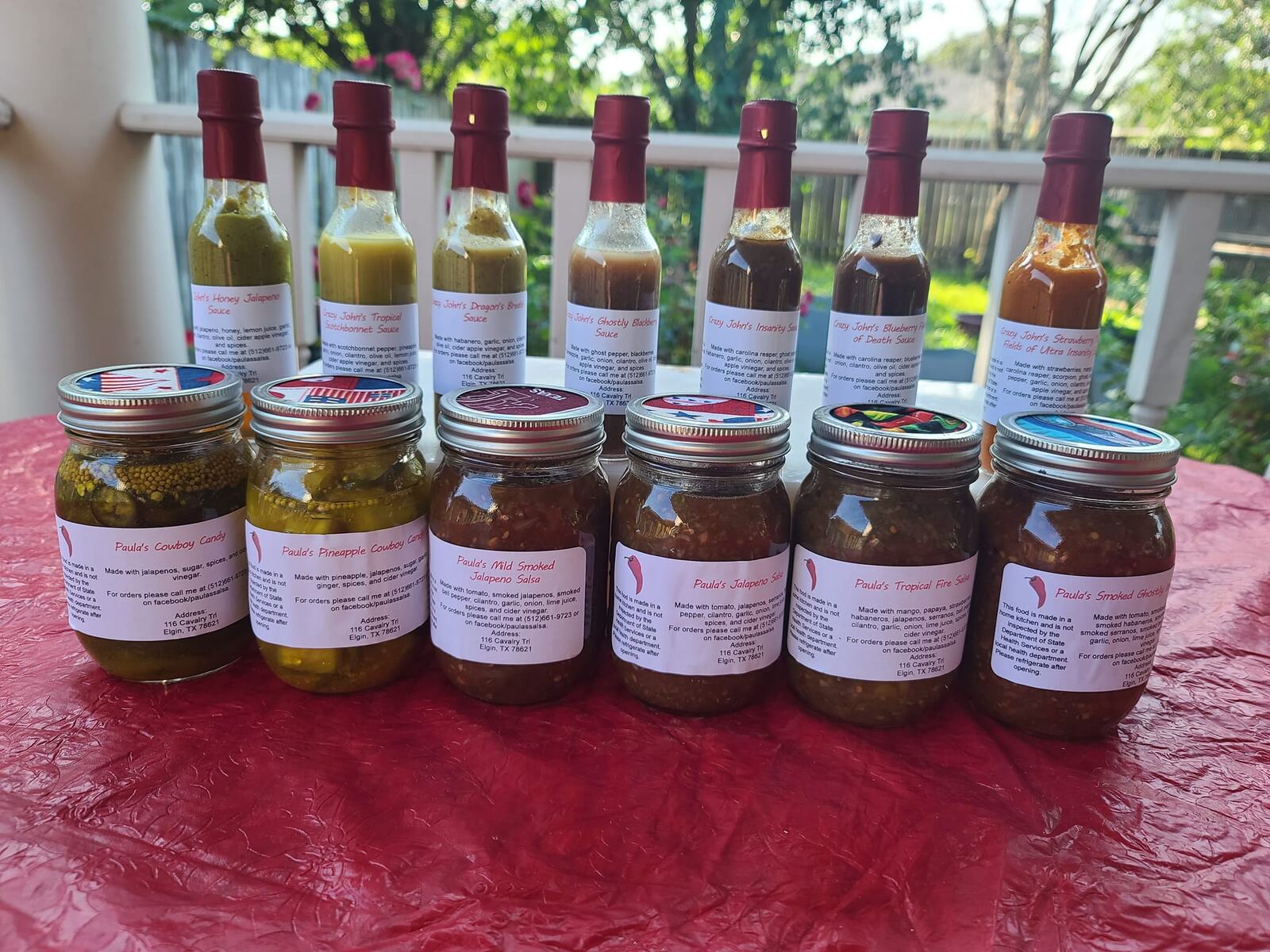 The full lineup of Paula and Crazy John's hot sauces, salsas, cowboy candy and pickles on a deck table